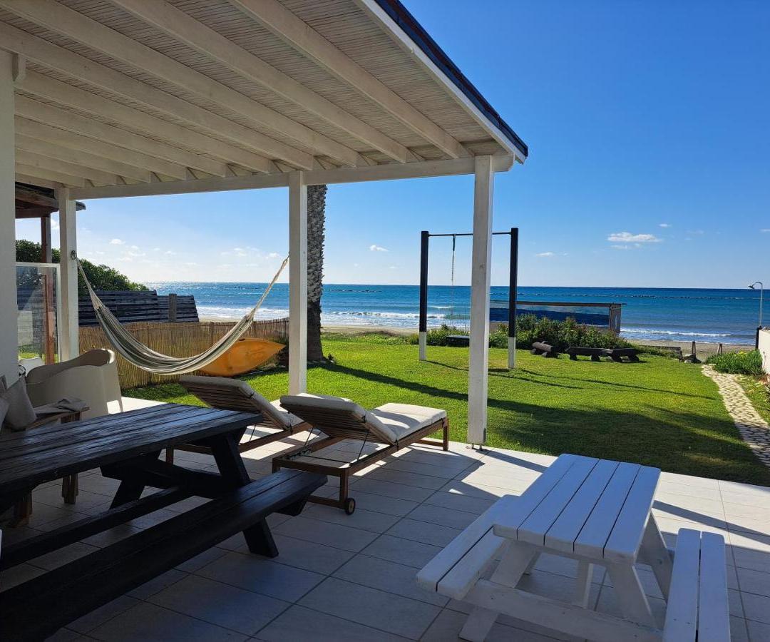 a patio with a hammock and a view of the ocean at Ammos Beachfront Villa Paradise in Larnaca