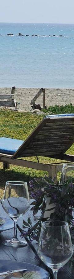 a table with glasses and a bottle of wine on the beach at Ammos Beachfront Villa Paradise in Larnaca
