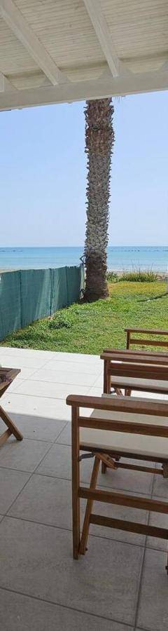 a porch with a bed and chairs and the ocean at Ammos Beachfront Villa Paradise in Larnaca